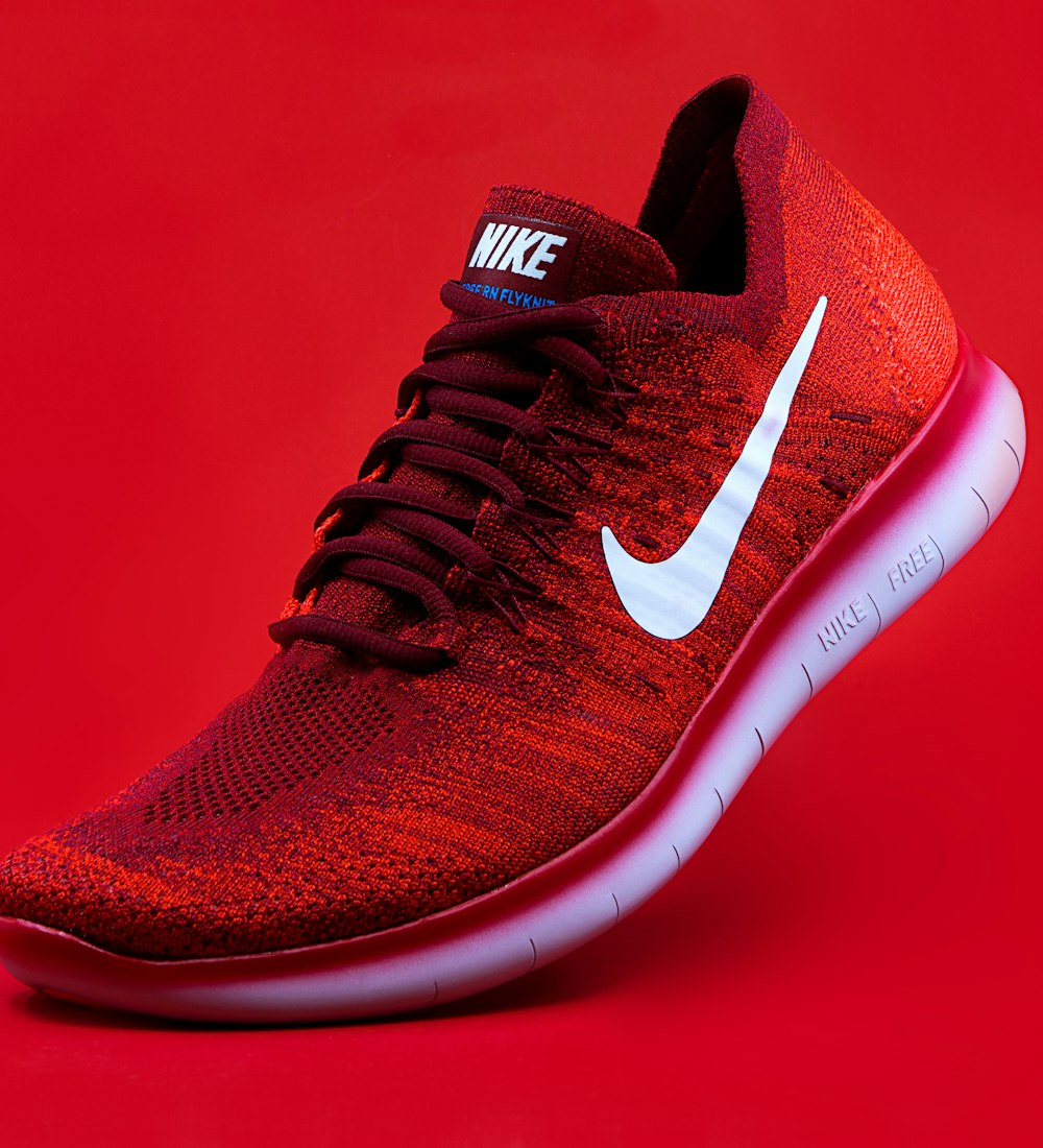 A red knit running shoe against a red backdrop